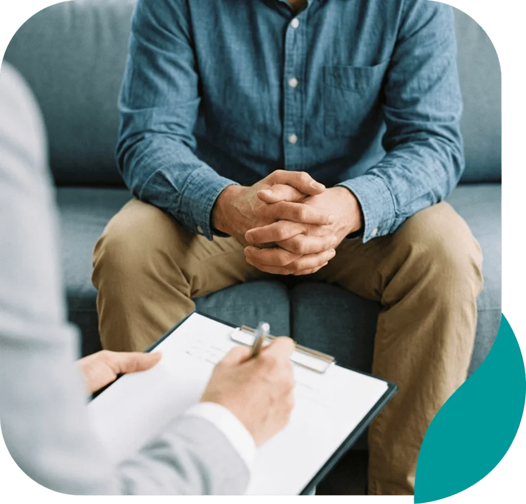 Client with clasped hands during a counseling session as the therapist takes notes