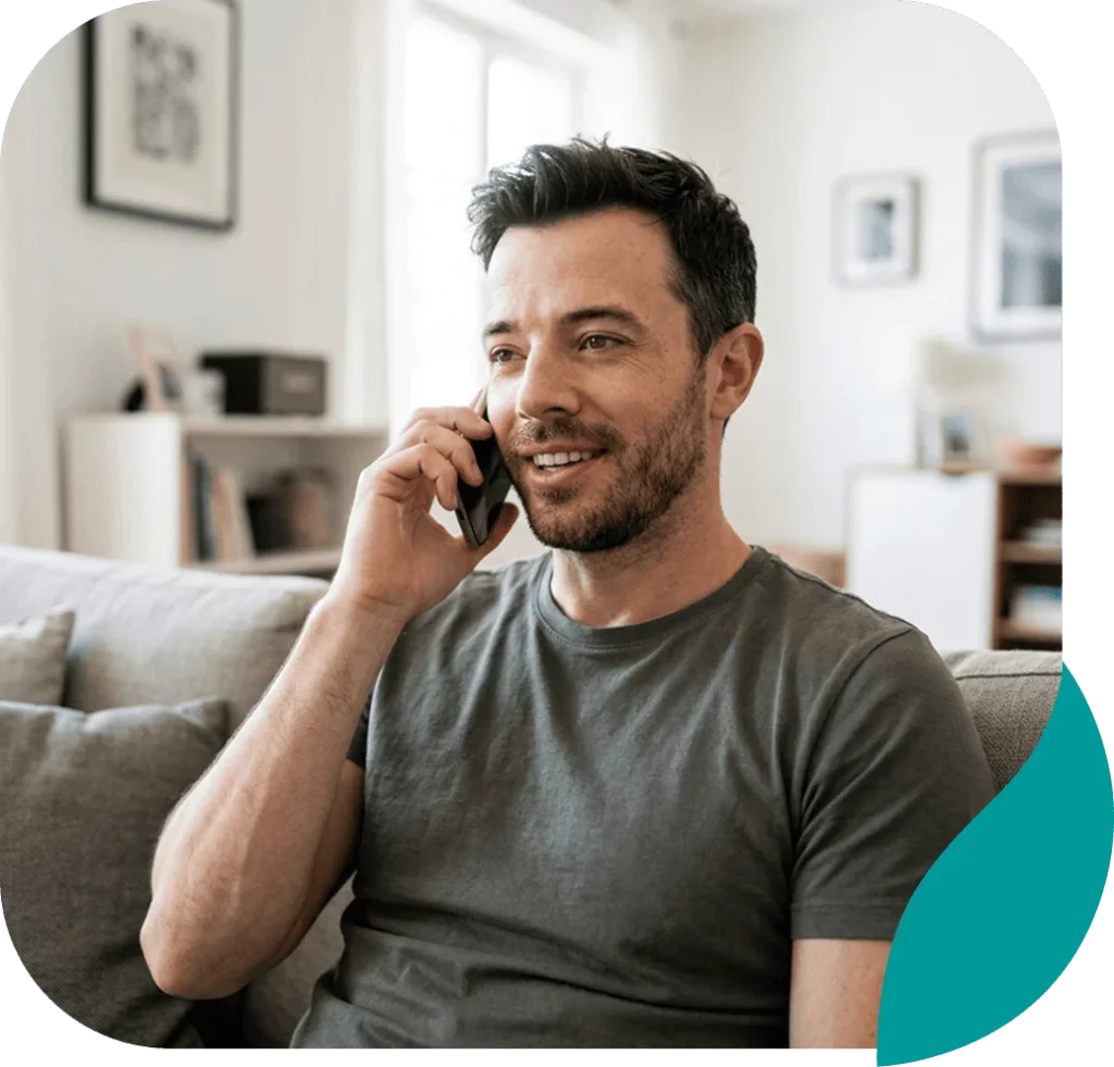 Smiling man talking on his phone while relaxing on a sofa at home